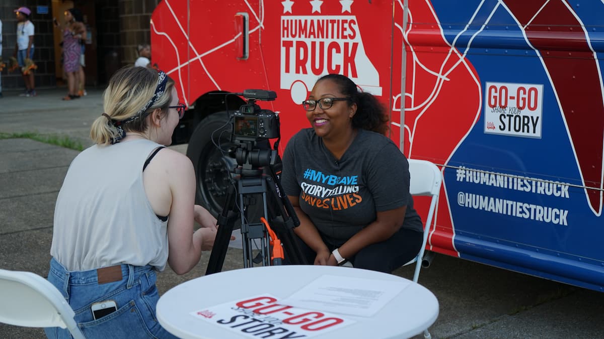 A woman is interviewed in front of the Humanities Truck.